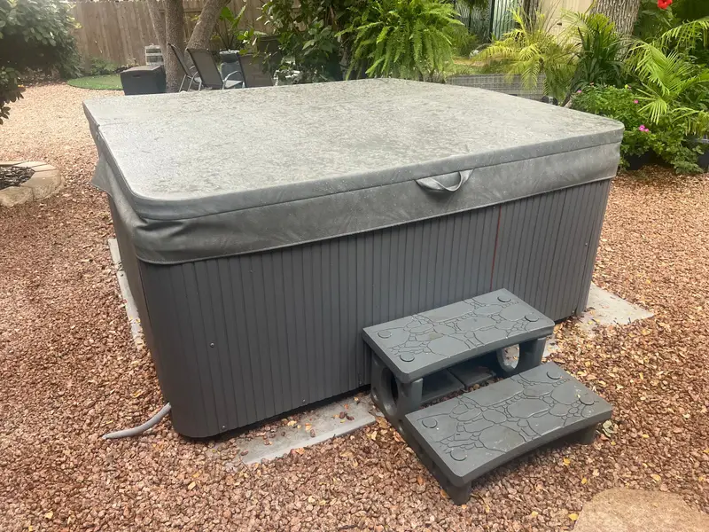 Covered hot tub with steps on a gravel pad