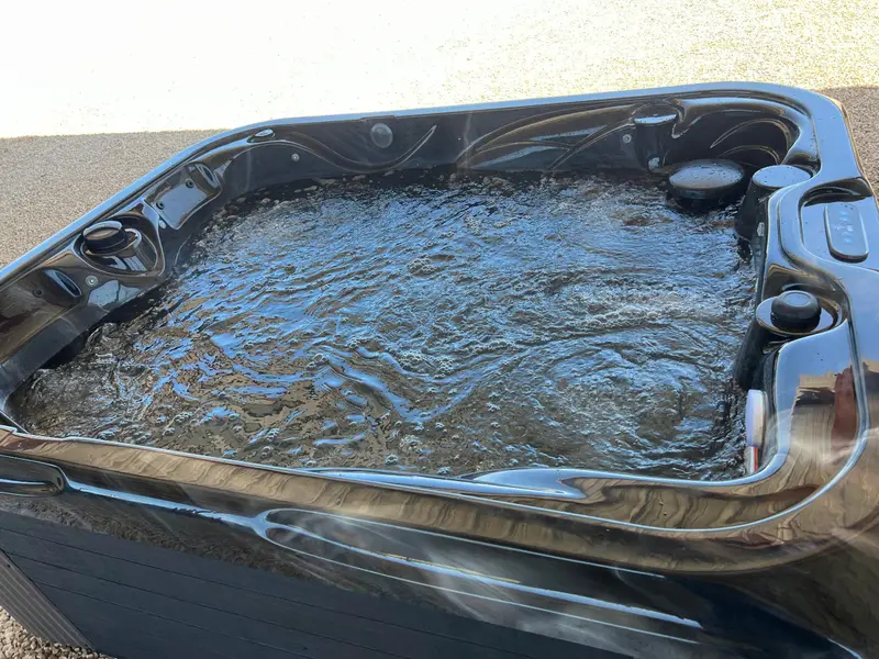 An uncovered dark-shell tub in the sun