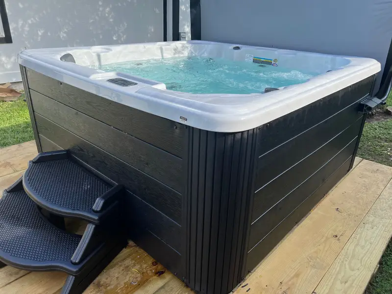 Dark-cabinet hot tub with steps on a new deck