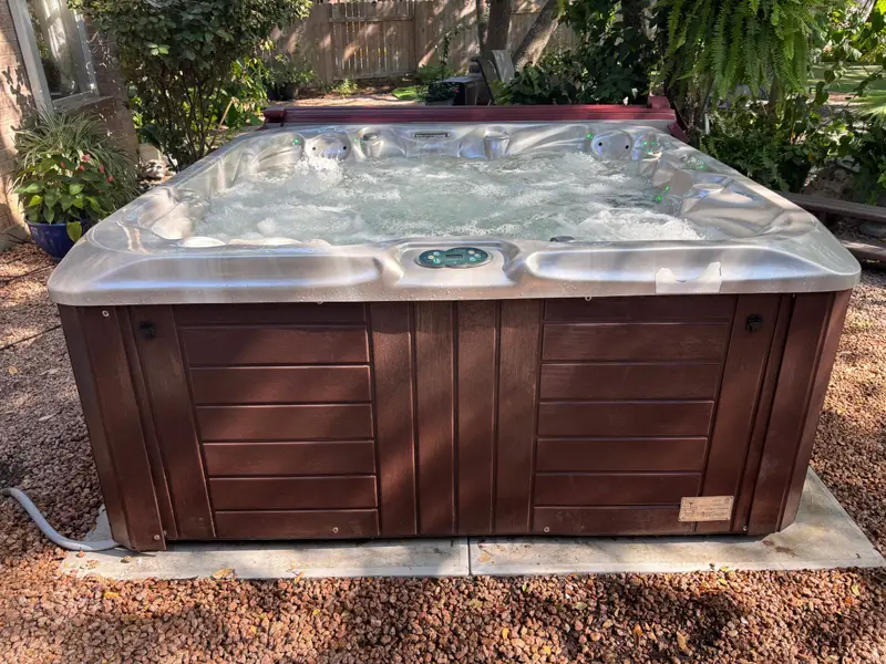 Hot tub with a wood-panel cabinet in a backyard